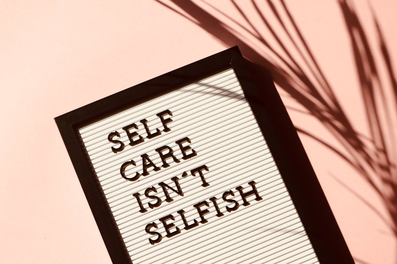 Services Letter board displaying 'Self Care Isn't Selfish' with artistic shadow on pink background.