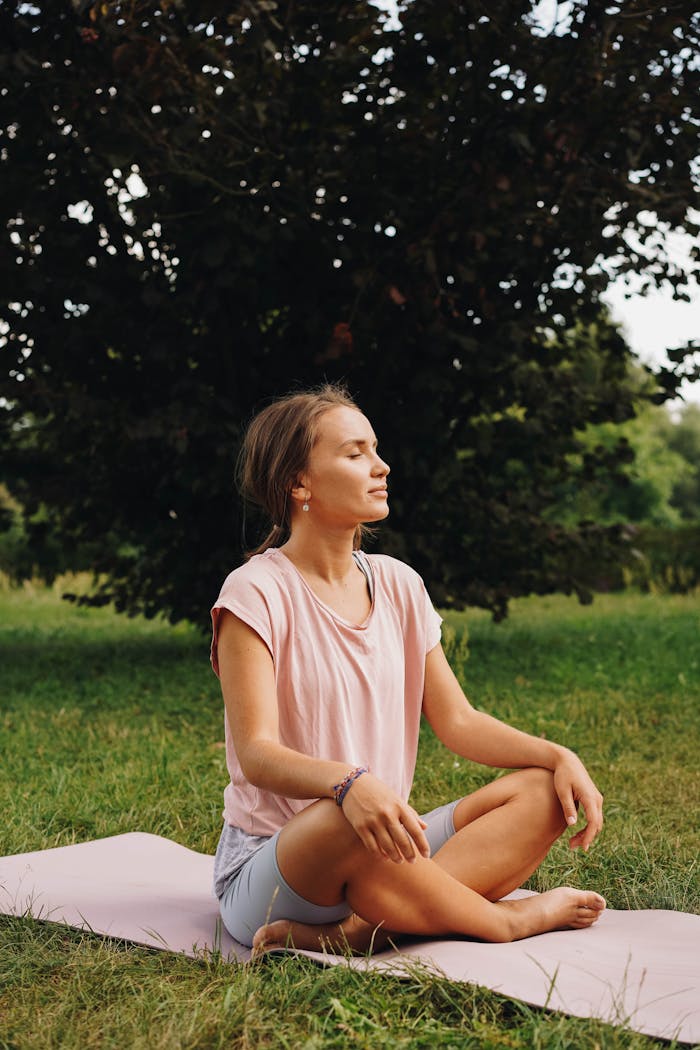 Crafting Captivating Headlines: Your awesome post title goes here A woman sits peacefully on a yoga mat outdoors, practicing meditation in a serene park setting.